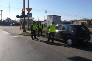 Policjant w asyście pracownika SOK kontroluje pojazd przy przejeździe kolejowym