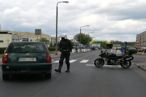 Policjant motocyklista podchodzi do zatrzymanego pojazdu