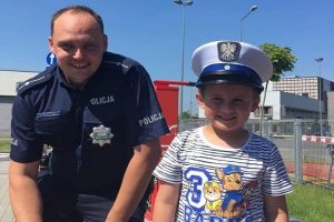 Policjant z chłopcem z przedszkola, który założył policyjną czapkę