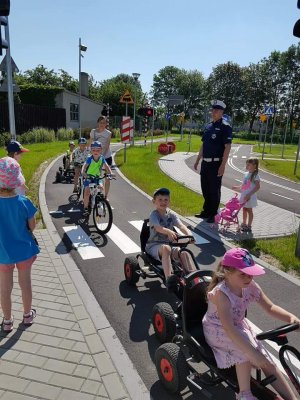 Policjant z dziewczynką przed przejściem dla pieszych w miasteczku