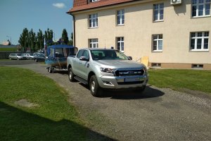 Policyjny radiowóz marki Ford z przyczepą na której znajduje się łódz