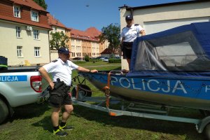 Policjantka na łodzi motorowej, obok łodzi dowódca patrolu