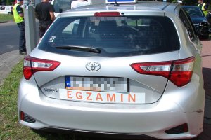 Pojazd egzaminacyjny Toyota, na drugim planie pracujący policjanci