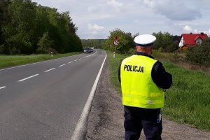 Na zdjęciach funkcjonariusz dokonujący kontroli drogowej