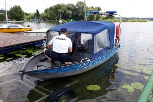 Policjant przy łodzi motorowej.