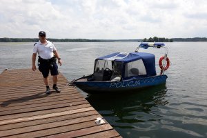 Policjant przy łodzi motorowej.