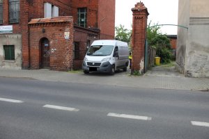 Policjant prowadzi oględziny roweru i samochodu na miejscu wypadku.