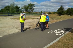 policjanci kontrolują przemieszczających się rowerzystów po drodze rowerowej