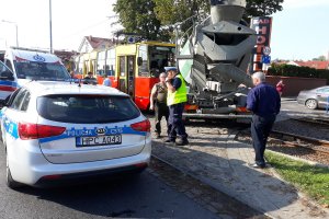 policjant i dwie osoby postronne radiowóz oraz tramwaj z ciężarowym mercedesem