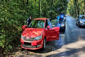 Po lewej stronie drogi stoi skoda fabia a za nią nieoznakowany radiowóz BMW z włączonym niebieskim światłem błyskowym.