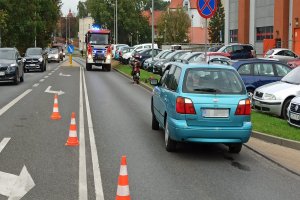 Miejsce kolizji drogowej. Na prawym pasie ruchu stoi Nissan, za nim pojazd straży pożarnej. Miejsce wygrodzone pachołkami.