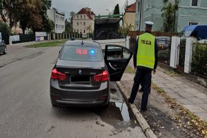 Policjant stojący obok radiowozu