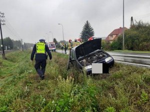 Policjant na poboczu obok rozbitego forda.