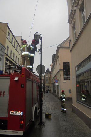 Strażacy demontują lampę uliczną