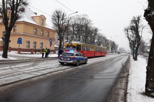 Stojący tramwaj po zdarzeniu. Obok stoi radiowóz na światłach błyskowych i uczestnicy zdarzenia z policjantami.