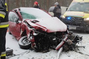 Rozbity Peugeot. Za nim stoi karetka pogotowia. Obok pojazdów widać strażaków