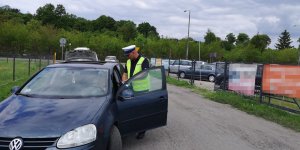 Policjant stoi obok kontrolowanego pojazdu