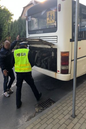 Dwóch mężczyzn stoi koło autobusu z otwartą pokrywą silnika