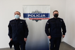 Dwóch policjantów na tle baneru Policja