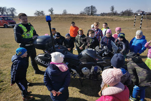 policjant z grupą dzieci stoi na dworzu