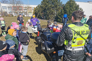 policjant stoi odwrócony plecami. Przed nim stoją dzieci