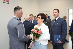 komendant miejski policji w grudziądzu przyjmuje gratulacje od kobiety przedstawiciela urzędu gminy grudziądz, za kobietą stoi dyrektor zakładu karnego w grudziądzu