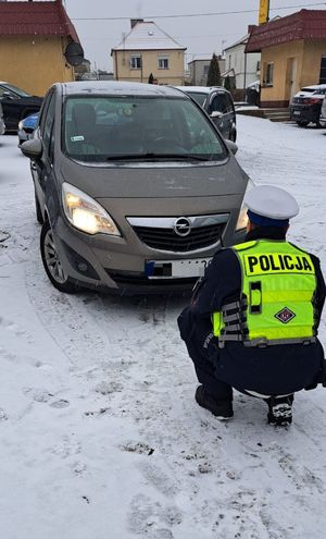 policjant w trakcie sprawdzania oświetlenia pojazdu