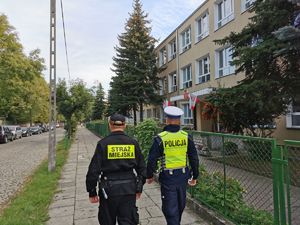 Policjant ze strażnikiem miejskim przy szkole