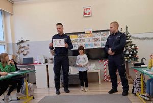 policjanci z dzieckiem prezentujący jego pracę