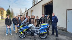 uczniowie z policjantem przy motocyklu służbowym