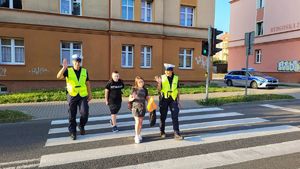 policjanci przechodzący przez przejście dla pieszych z uczniami