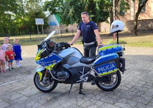 policjant przy motocyklu opowiada dzieciom o zasadach bezpieczeństwa