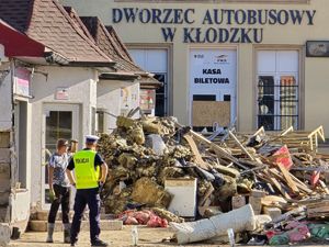 policjant z mieszkańcem przy zniszczonym budynku