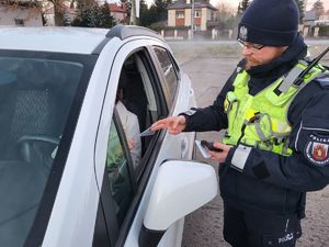 policjant wręczający skrobaczkę w trakcie kontroli drogowej