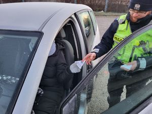 policjant wręczający skrobaczkę w trakcie kontroli drogowej