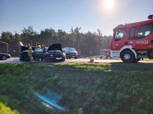 wóz strażacki i strażacy przy rozbitych pojazdach na skrzyżowaniu