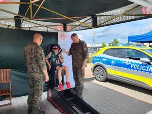 chłopiec na symulatorze czołowego zderzenia w towarzystwie żołnierzy żandarmerii