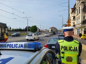 policjant stojący przy radiowozie i nadzorujący ruch