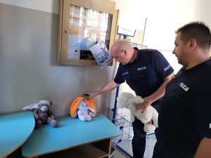 komendanci umieszczający maskotkę w poczekalni komendy