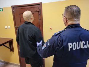 sprawca rozboju w towarzystwie policjanta przed pomieszczeniem dla osób zatrzymanych