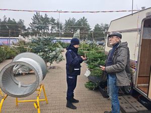 policjantka kontrolująca stoisko sprzedaży choinek