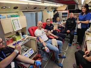 Grupa osób w tym policjanci, oddaje krew wewnątrz krwiobusa.