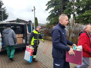 nadkomisarz Tomasz Manuszewski niosący dary razem z pracownikami schroniska